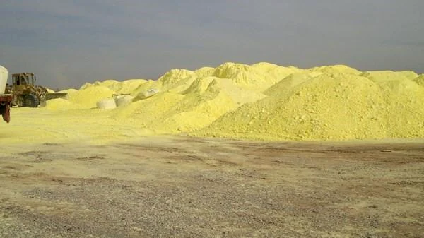 Yellow sulfur stockpiles in an open industrial storage yard